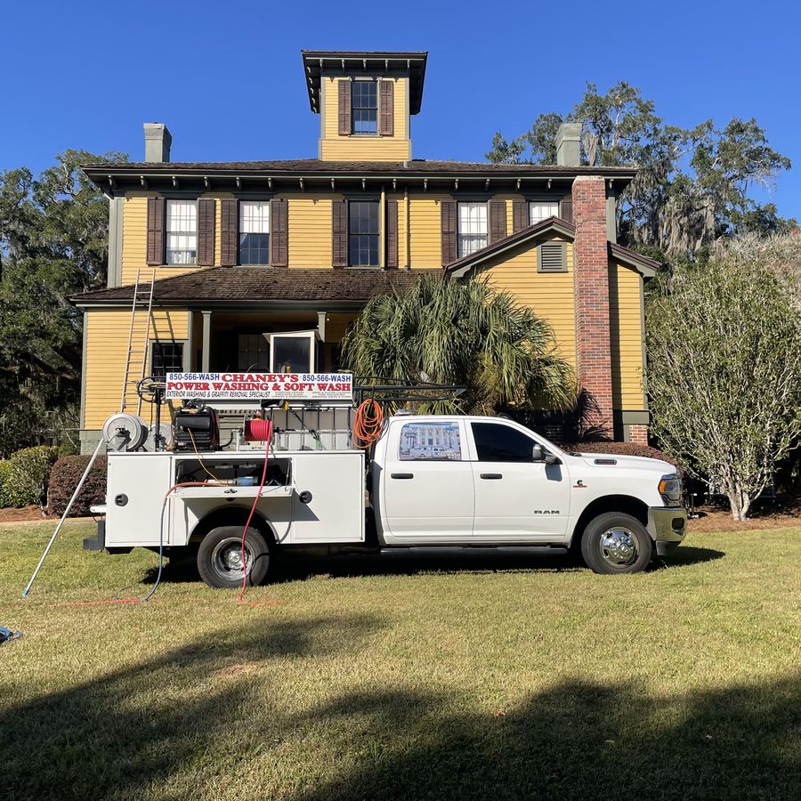 A Chaney's truck and ladder set up beside a two-storey historic timber house with painted siding and shutters.