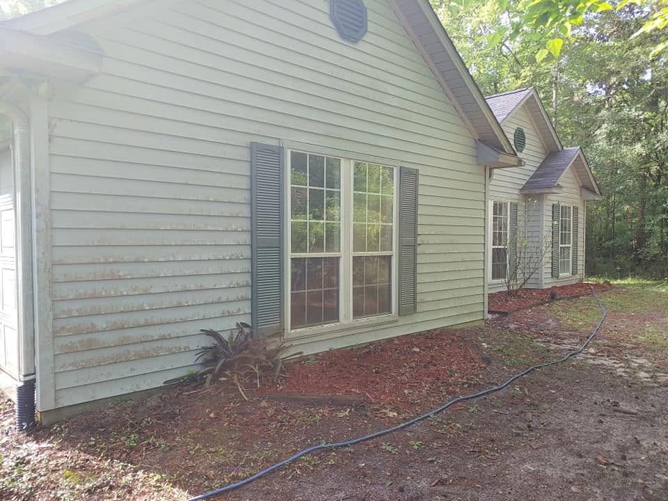 Before: pale lap siding on the side of a house, streaked and stained brown across the lower boards.
