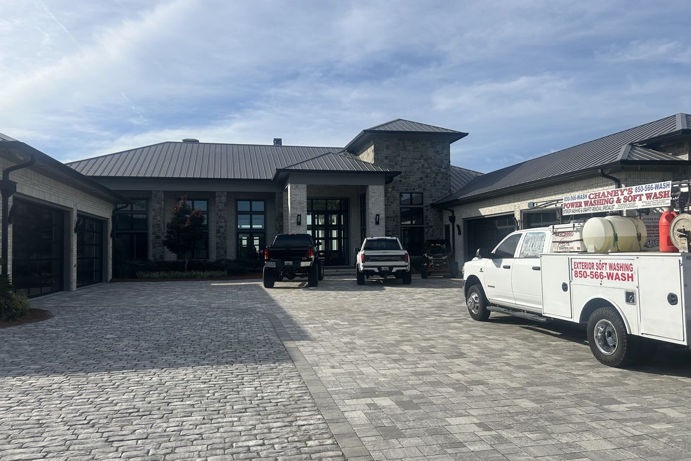 A Chaney's service truck on the paver driveway of a large single-storey brick home with a standing-seam metal roof.